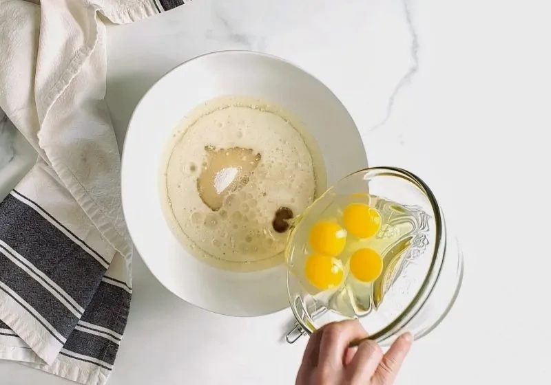 Eier werden in eine Schüssel mit Öl, Zucker und Vanille für glutenfreie Torte mit Vanille eingerührt