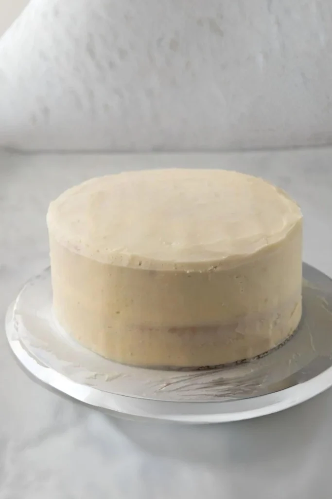 Zweilagige glutenfreie Torte mit glattem Frosting vor der Dekoration auf silberner Tortenplatte