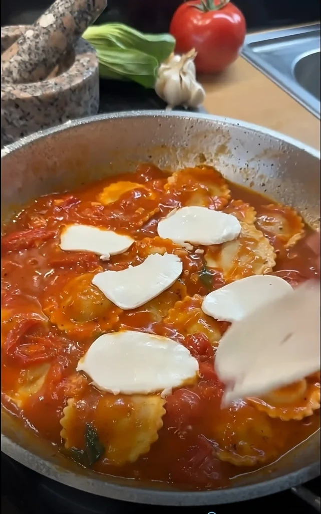 Frische Ravioli in Tomatensauce werden mit Mozzarellascheiben belegt – die Basis für eine cremige, schnelle Sauce zu Ravioli.