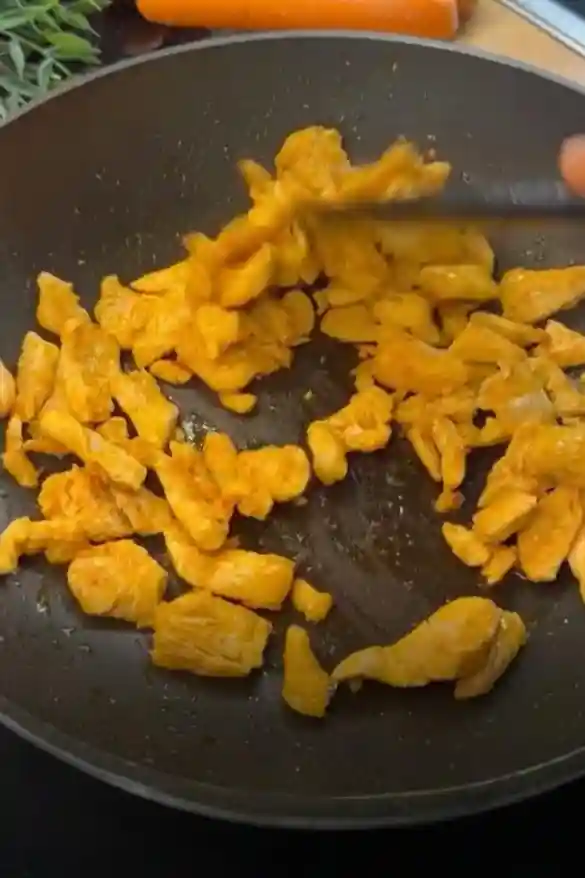 Gewürztes Hähnchenfilet wird in der Pfanne goldbraun für gebratene Asia Nudeln angebraten