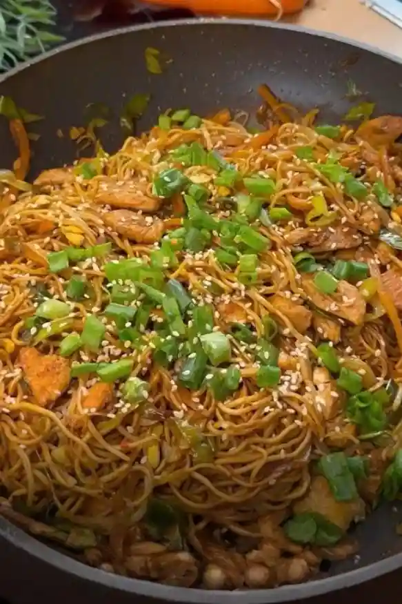 Asiatische gebratene Nudeln mit Gemüse und Hähnchen in der Pfanne mit Sesam und Frühlingszwiebeln