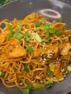 Asiatische gebratene Nudeln mit Gemüse und Hähnchen in Schüssel, mit Sesam und Frühlingszwiebeln garniert