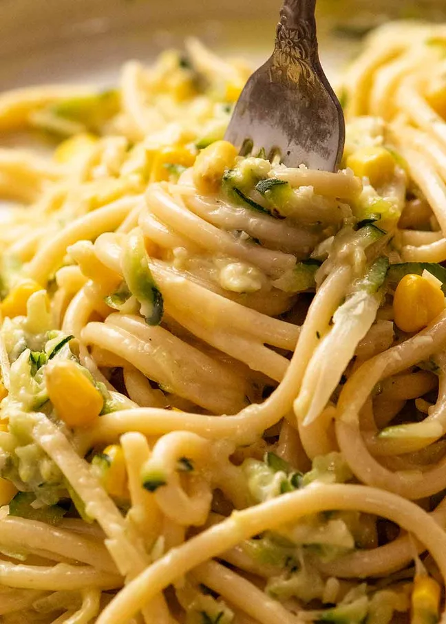 Nahaufnahme von Spaghetti mit Zucchinisauce, Sahne, Mais und Parmesan – cremige Zucchini Pasta Sauce auf der Gabel.