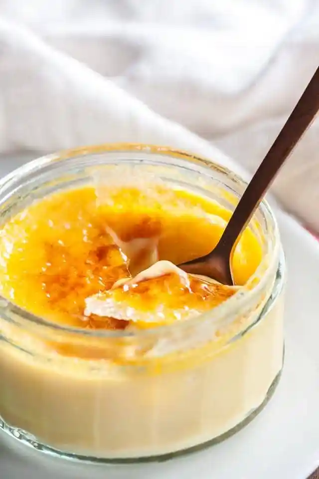 Crème Brûlée mit karamellisierter Kruste im Glas, mit Löffel serviert