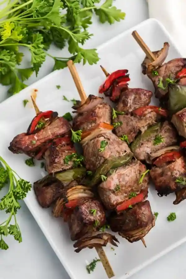 Wie lange brauchen Fleischspieße in der Heißluftfritteuse – servierte Rindfleischspieße mit Paprika und Zwiebeln auf einem weißen Teller