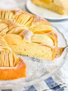 Frisch gebackener versunkener Apfelkuchen mit Rührteig und Apfelspalten auf einer Glasplatte