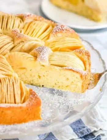 Frisch gebackener versunkener Apfelkuchen mit Rührteig und Apfelspalten auf einer Glasplatte