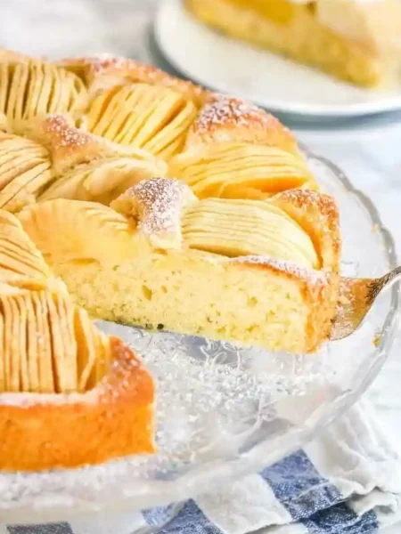 Frisch gebackener versunkener Apfelkuchen mit Rührteig und Apfelspalten auf einer Glasplatte
