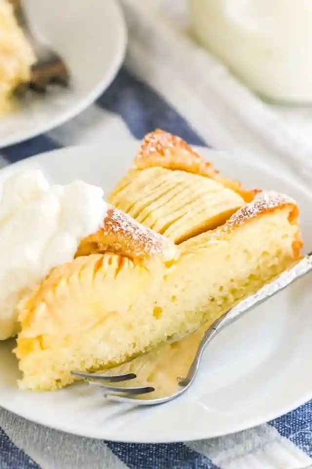 Ein Stück versunkener Apfelkuchen mit Schlagsahne serviert – klassisches Oma Rezept