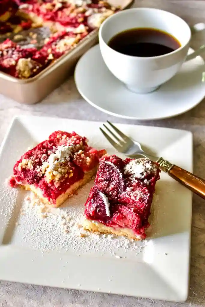 Pflaumenkuchen auf dem Blech mit Streusel serviert mit Kaffee