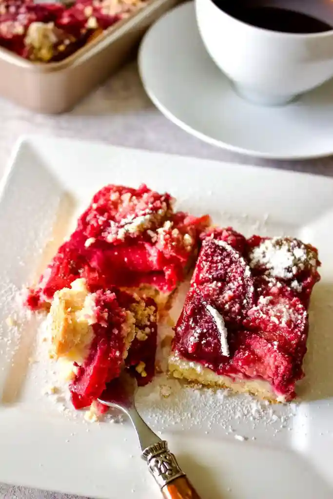 Pflaumenkuchen auf dem Blech mit Streusel serviert auf Teller mit Gabel