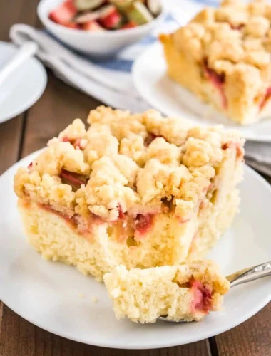 Omas saftiger Rhabarber Streuselkuchen vom Blech mit knusprigen Streuseln und fluffigem Teig, serviert auf einem weißen Teller.