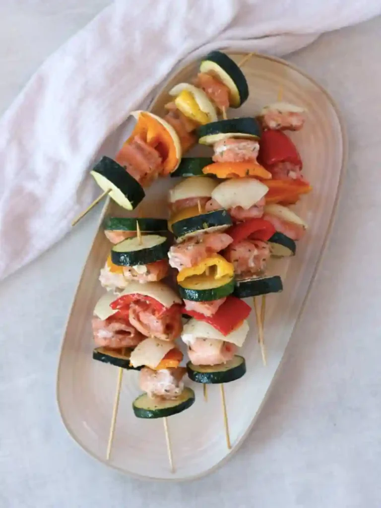 Wie lange brauchen Fischspieße in der Heißluftfritteuse – rohe Lachs-Gemüse-Spieße mit Zucchini und Paprika auf einem Teller