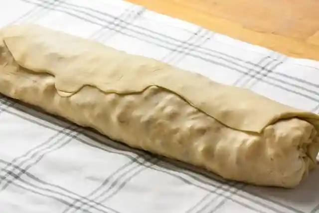Apfelstrudel Rezept mit Strudelteig – frisch aufgerollter Strudel vor dem Backen
