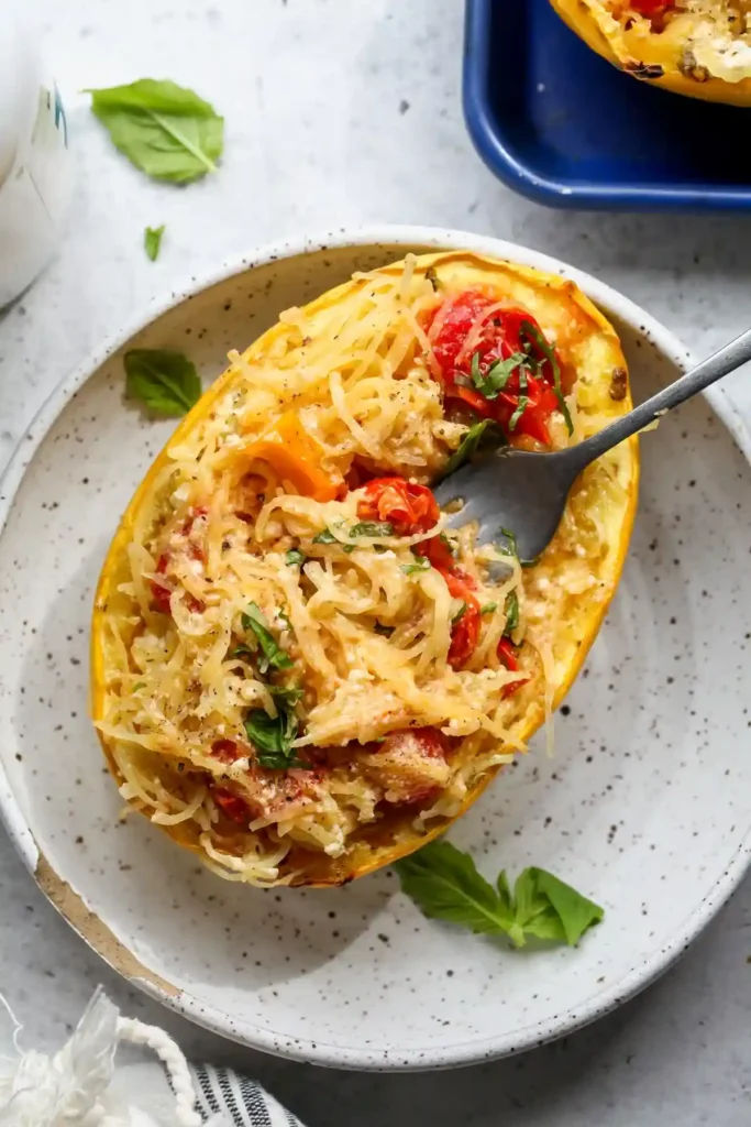 Spaghettikürbis mit Feta und Tomaten im Backofen – cremiger Spaghetti Kürbis mit Käse, gebackenen Kirschtomaten und frischen Kräutern.