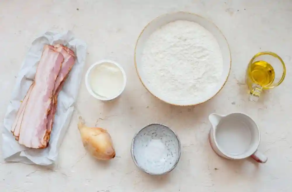 Flammkuchen Zutaten – Mehl, Speck, Zwiebel, Crème fraîche, Öl, Wasser und Salz für den klassischen Elsässer Flammkuchen