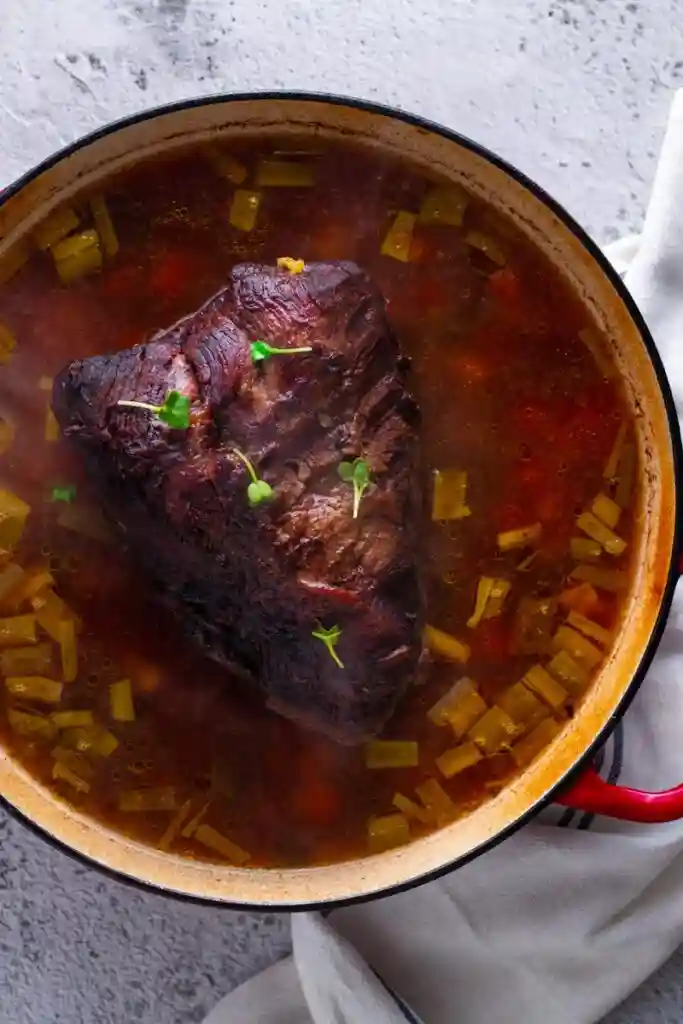Sauerbraten schmoren im Sud mit Gemüse – traditionelles Rezept