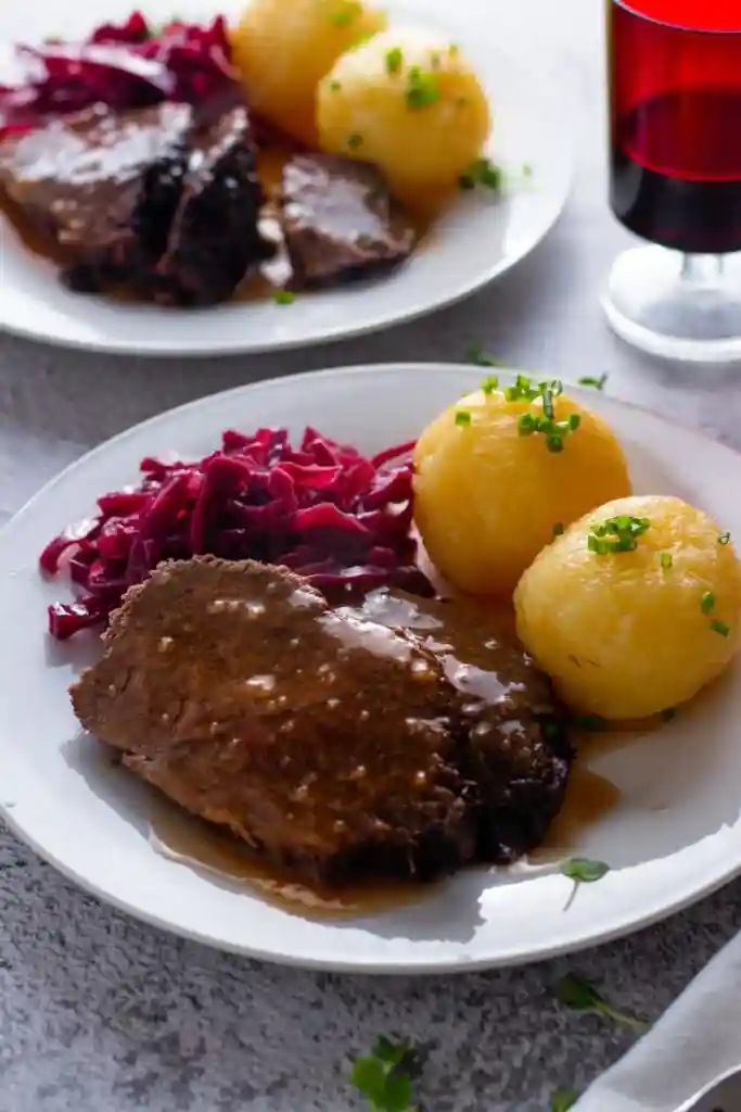 Traditioneller deutscher Sauerbraten mit Rotkohl und Kartoffelklößen – klassisches Sauerbraten Rezept