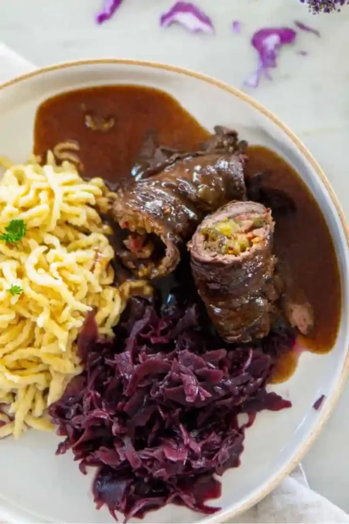 Klassische Rinderrouladen mit Soße, Spätzle und Rotkohl serviert