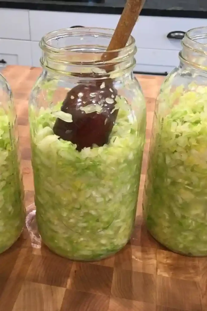Frisch gehobelter Kohl wird ins Glas gefüllt – Schritt im Sauerkraut Rezept zum Selbermachen