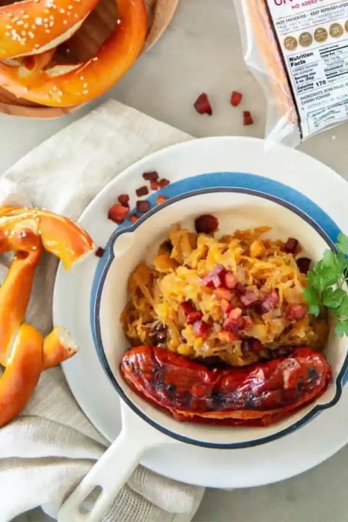 Sauerkraut mit Speck und Zwiebeln Rezept serviert mit Bratwurst und Brezeln