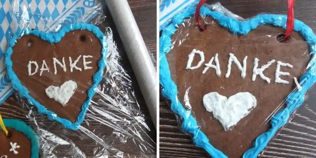 Lebkuchenherz mit blauer Zuckerguss-Dekoration und weißem Herz verziert, in Folie verpackt – klassisches Lebkuchenherz Geschenk mit Aufschrift „Danke“.