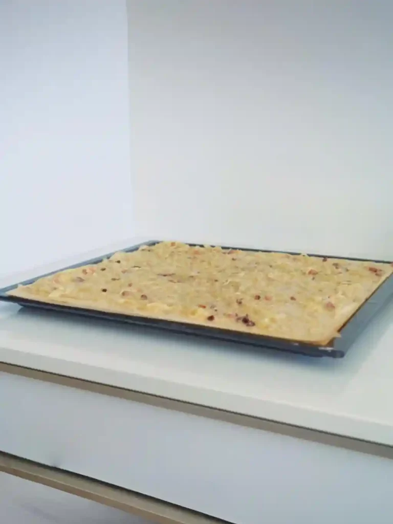 Zwiebelkuchen vom Blech mit Hefeteig vor dem Backen – Zwiebel-Schmand-Belag mit Speck