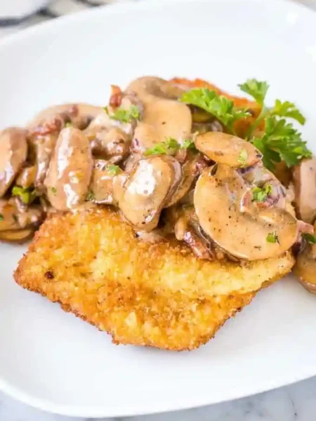 Knuspriges Jägerschnitzel DDR Rezept mit cremiger Champignonsoße auf einem Teller, garniert mit Petersilie.