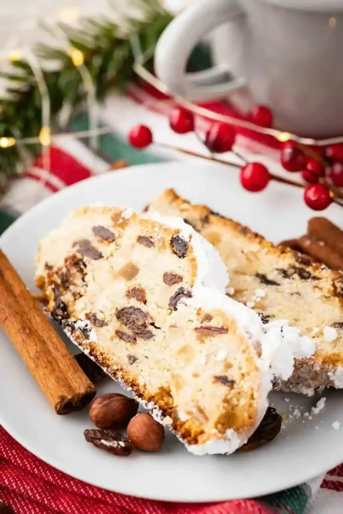Saftiger Dresdner Stollen mit Marzipan aufgeschnitten auf einem Teller – Omas Christstollen Rezept mit Rosinen, Zitronat und Puderzucker.
