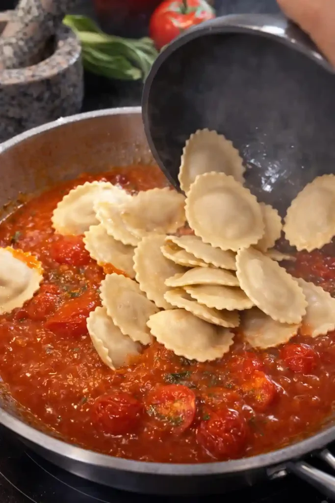 Ravioli werden in die Pfanne mit Tomatensauce gegeben – Zubereitung von Ravioli mit Tomatensauce und klassischen Soßen zu Ravioli