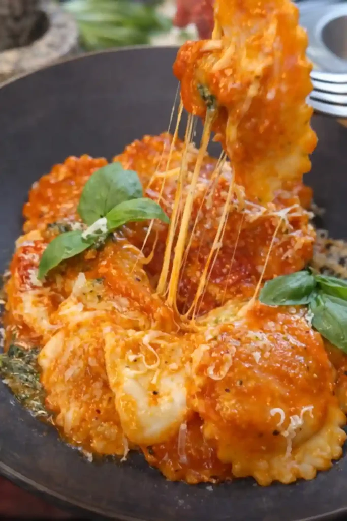 Ravioli mit Tomatensauce auf dem Teller, mit geschmolzenem Käse und Basilikum – cremige Soßen zu Ravioli