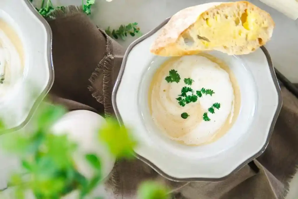 Spargelsuppe Rezept – cremige Spargelcremesuppe mit Kräutern und Brot angerichtet
