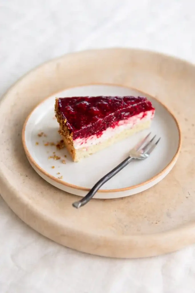 Stück Himbeertorte mit Sahne auf Teller – einfache Himbeer-Sahne-Torte mit Biskuitboden, Cremefüllung und fruchtiger Himbeerschicht