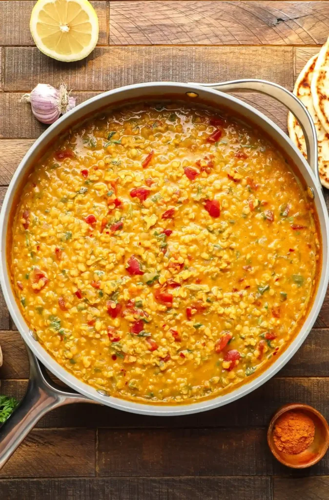 Rote Linsen Dal Curry Rezept – indisches veganes Dal Gericht mit roten Linsen, Tomaten und Gewürzen beim Köcheln in der Pfanne