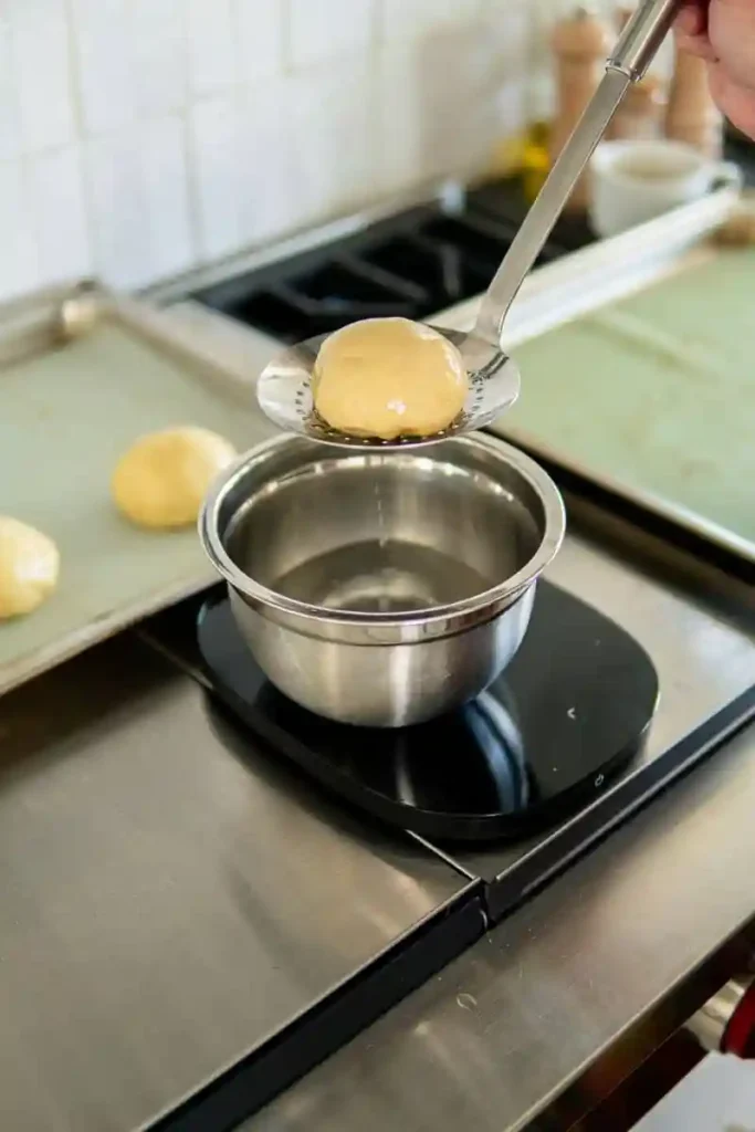 Laugenbrötchen selber machen – Teigling wird für das Laugenbrötchen Rezept in Lauge getaucht