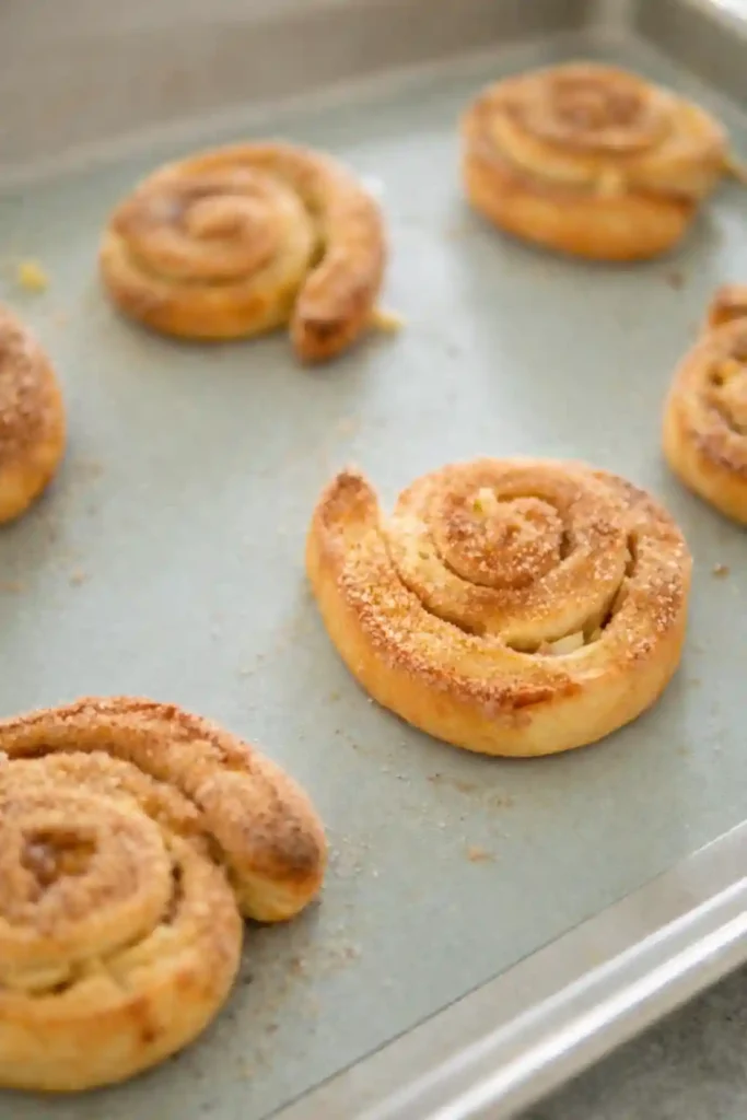 Frisch gebackene Apfelschnecken mit Hefeteig und Zimt nach Omas Apfelschnecken Rezept auf dem Backblech