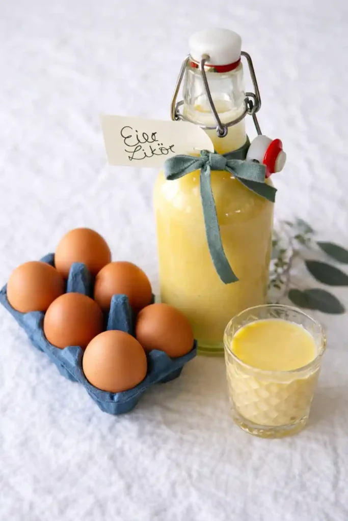 Omas Eierlikör Rezept DDR – selbstgemachter Eierlikör mit Rum in Glasflasche, daneben frische Eier und ein Likörglas