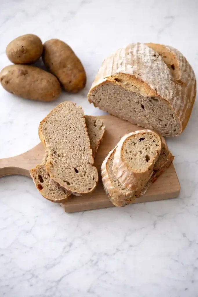 Omas Kartoffelbrot Rezept mit Sauerteig – frisch gebackenes Kartoffelbrot mit aufgeschnittenen Scheiben und Kartoffeln