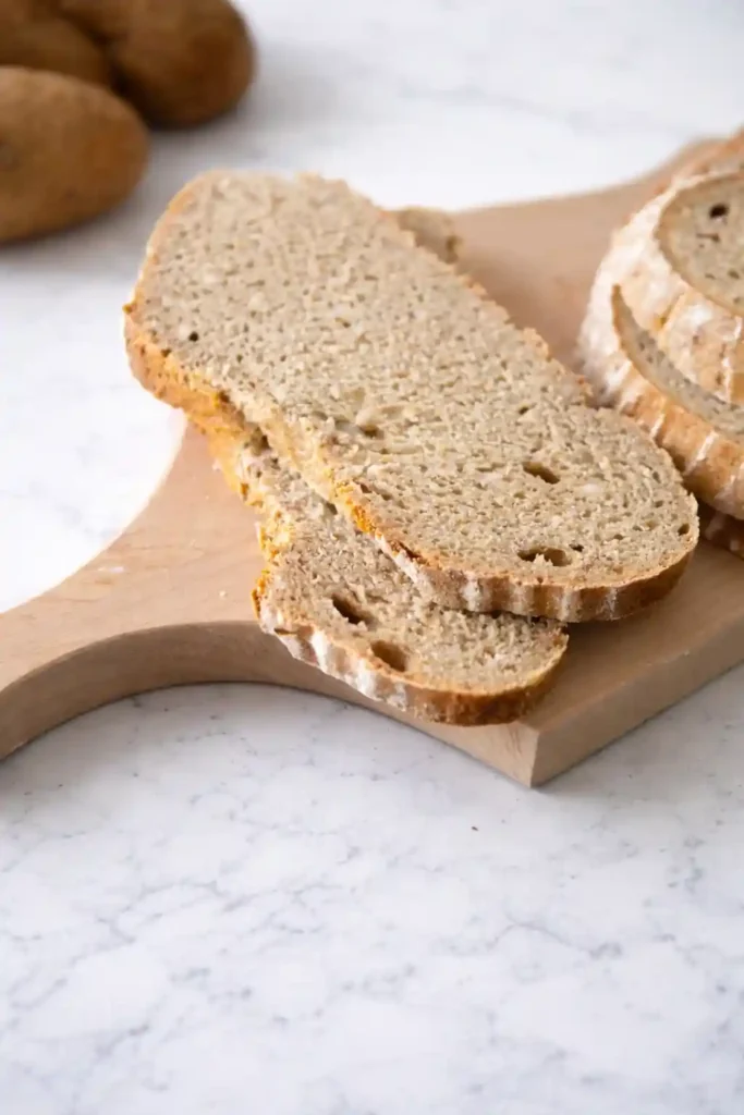 Omas Kartoffelbrot Rezept mit Sauerteig – aufgeschnittenes Kartoffelbrot mit lockerer Krume auf Holzbrett