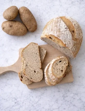 Omas Kartoffelbrot Rezept mit Sauerteig – frisch gebackenes Kartoffelbrot mit knuspriger Kruste und saftiger Krume, serviert mit Kartoffeln