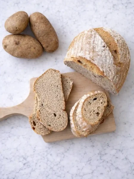 Omas Kartoffelbrot Rezept mit Sauerteig – frisch gebackenes Kartoffelbrot mit knuspriger Kruste und saftiger Krume, serviert mit Kartoffeln