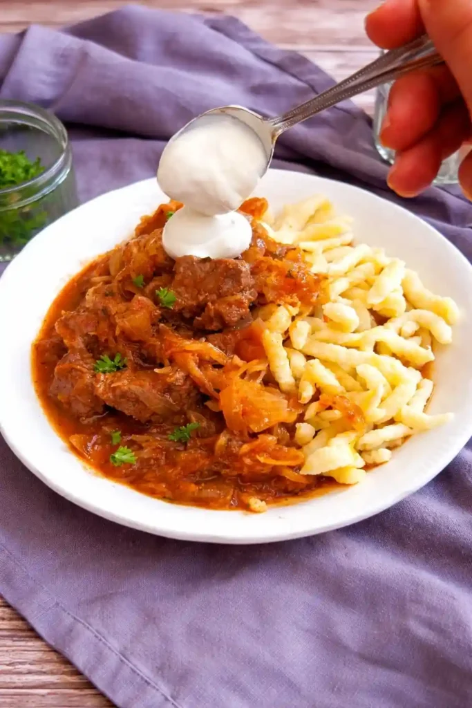 Szegediner Gulasch Rezept original mit Sauerkraut und Sauerrahm, serviert mit Spätzle