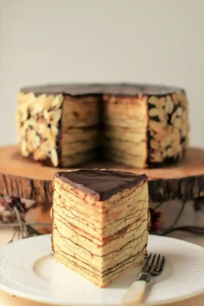 Saftiges Baumkuchen Rezept als angeschnittenes Stück mit feinen Schichten und Schokoladenglasur – Baumkuchen selbst gemacht