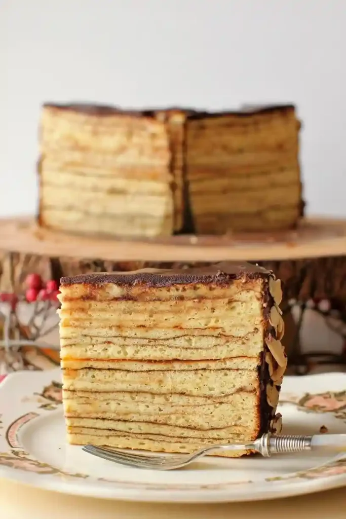 Saftiges Baumkuchen Rezept als Stück angeschnitten – klassischer Baumkuchen selbst gemacht mit feinen Schichten und Schokoladenglasur