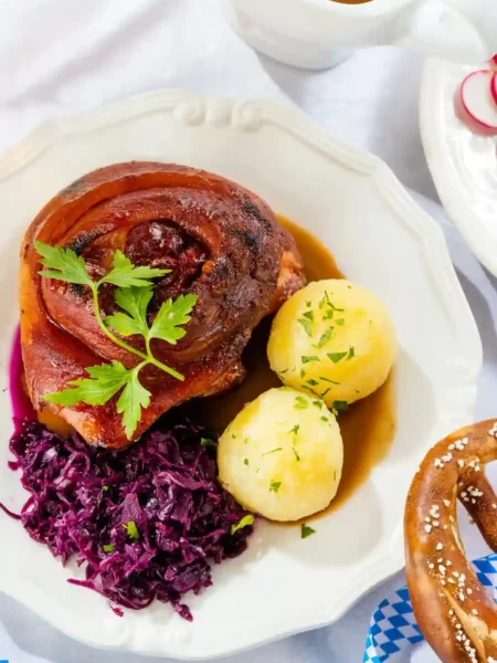 Bayerische Schweinshaxe im Backofen mit Vorkochen, knusprige Haxe im Ofen mit Rotkohl, Kartoffelklößen und Bratensoße