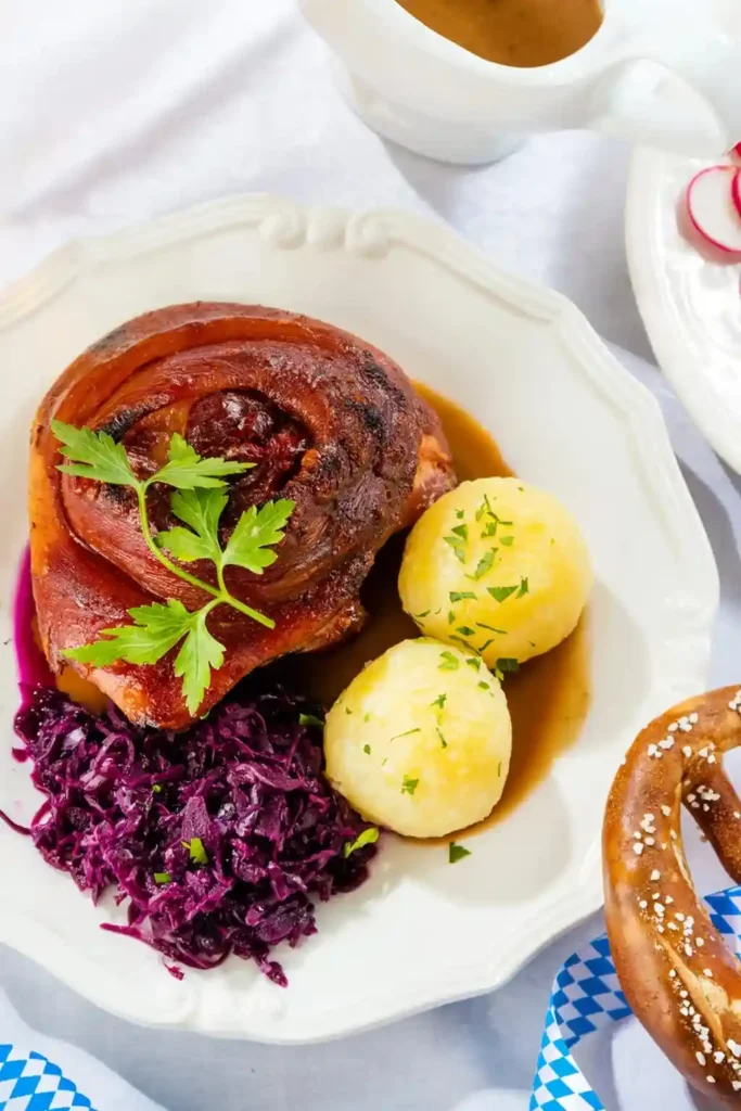 Bayerische Schweinshaxe im Backofen mit Vorkochen, knusprige Haxe im Ofen mit Rotkohl, Kartoffelklößen und Bratensoße