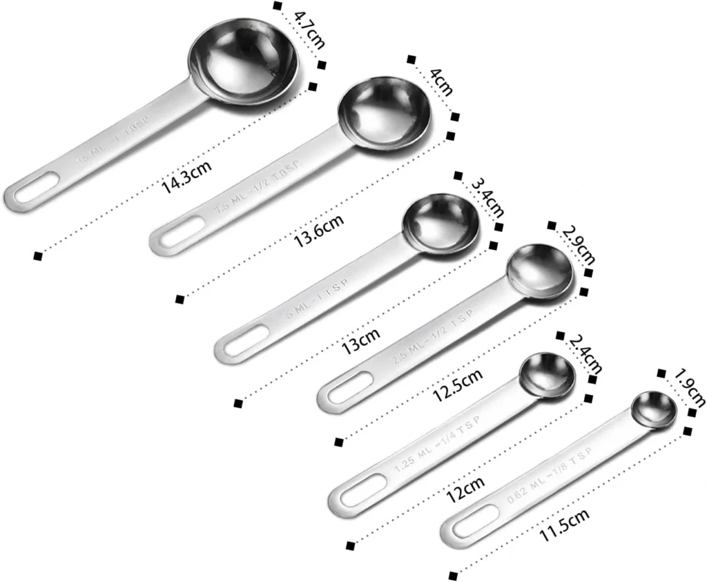 Edelstahl Messlöffel Set 6-teilig mit Gewürzen, Reis und Zucker auf grauem Hintergrund