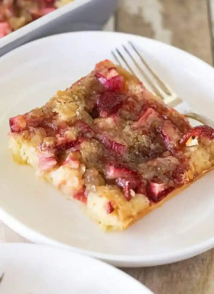 Stück Erdbeer Rhabarber Kuchen vom Blech auf einem Teller – saftiger Blechkuchen mit Erdbeeren und Rhabarber