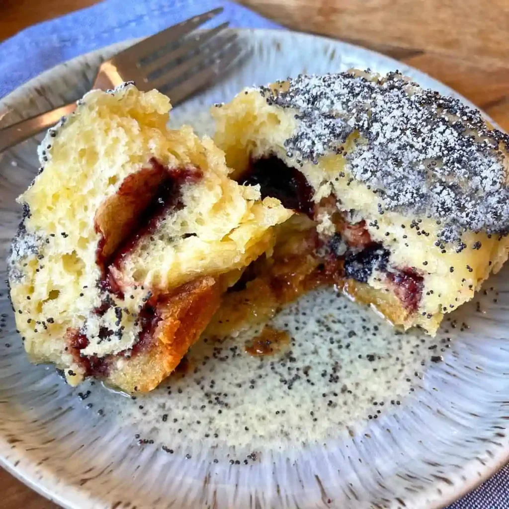 Aufgeschnittener Germknödel mit Pflaumenmus – fluffiger Hefeknödel mit Mohn und Puderzucker
