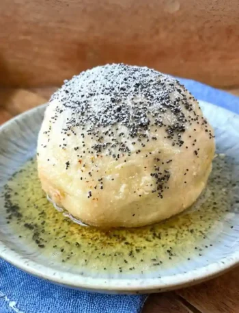 Germknödel mit Pflaumenmus – klassischer Germknödel mit Butter, Mohn und Puderzucker auf Teller